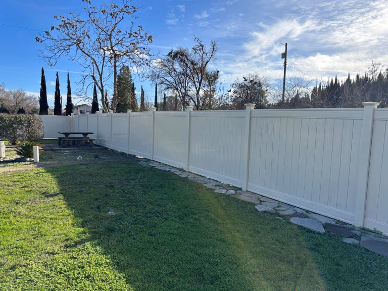 White vinyl privacy fence with decorative posts enclosing a residential backyard